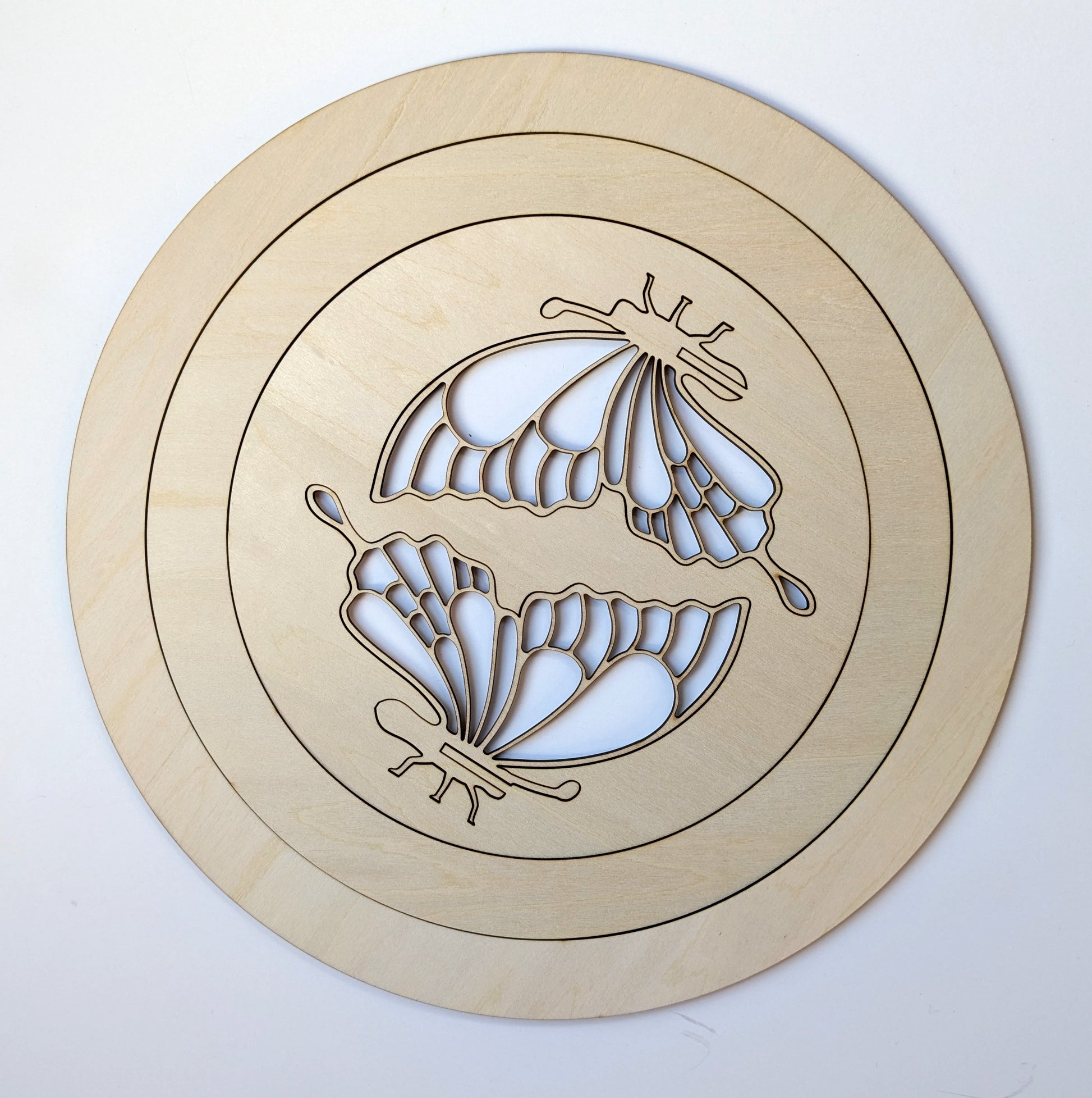 Wooden circular cutout with butterfly design on a white background