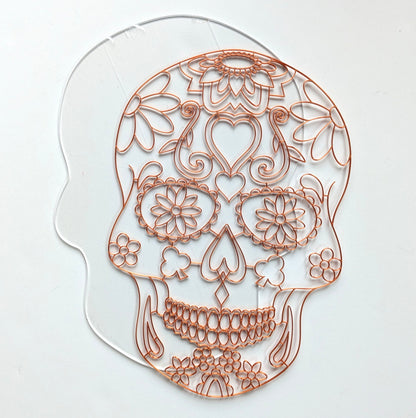 3D printed copper PLA sugar skull resin art template laid on a clear skull-shaped acrylic panel, showing floral and heart detail