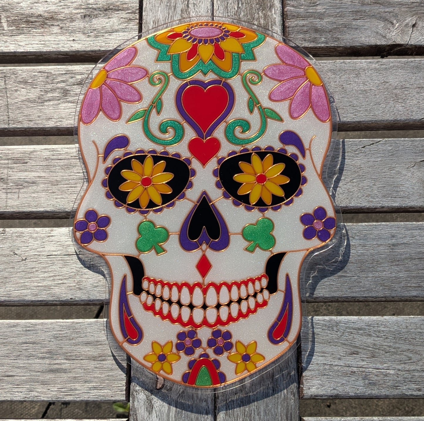 Completed sugar skull resin art piece with vibrant coloured resin poured into 3D printed template, showing pink, purple, green and red faux stained glass effect