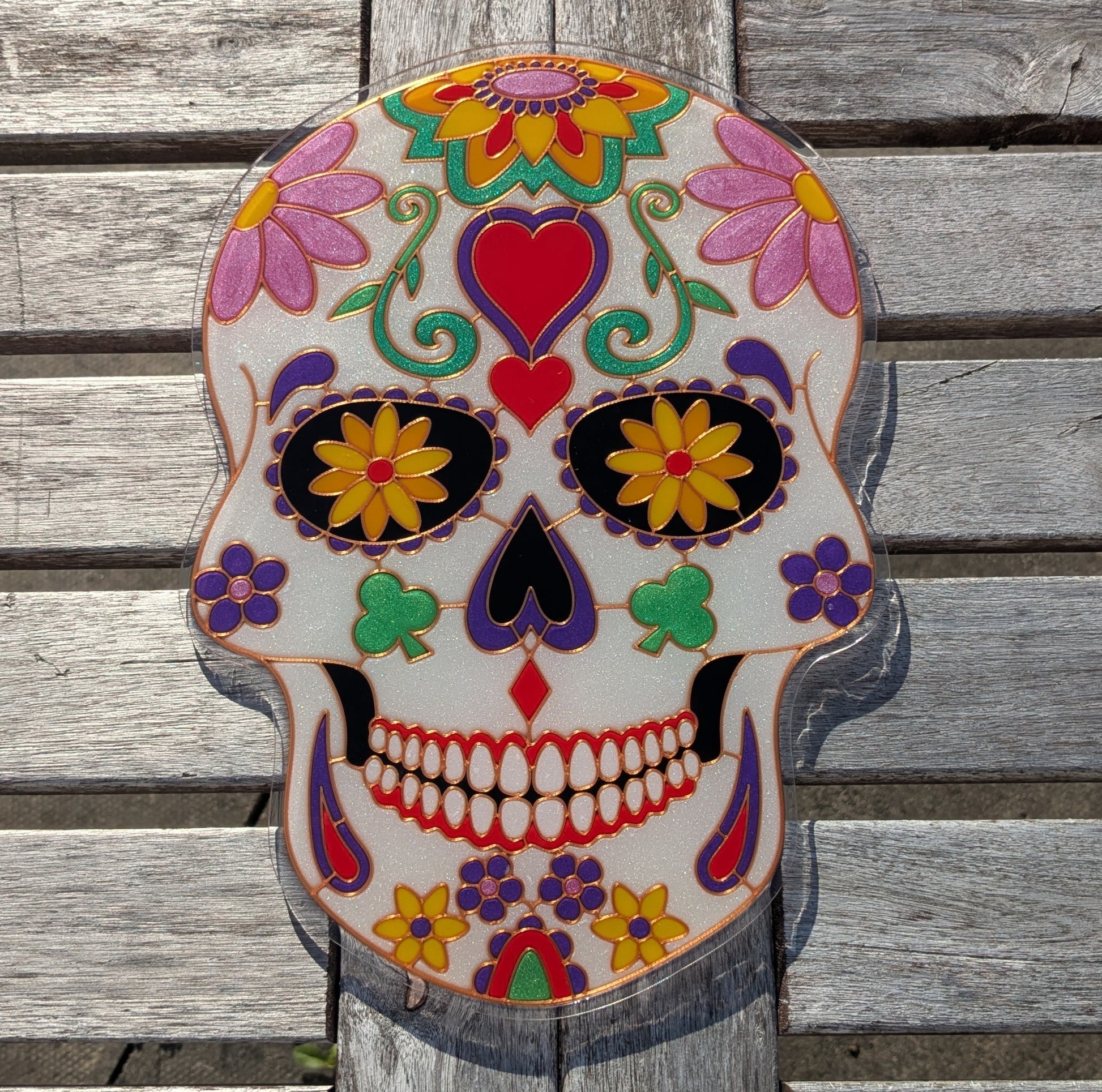Completed sugar skull resin art piece with vibrant coloured resin poured into 3D printed template, showing pink, purple, green and red faux stained glass effect